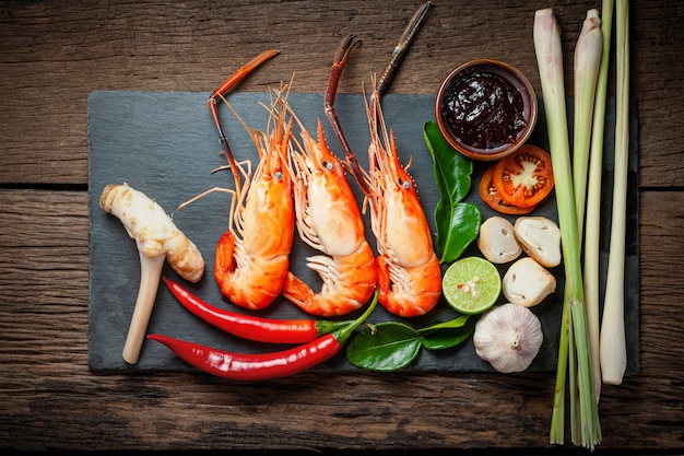 Ingredients of Thai food prepared for cooking. shrimps, chili, galangal, lemon grass, chili paste on black plate and wooden table.