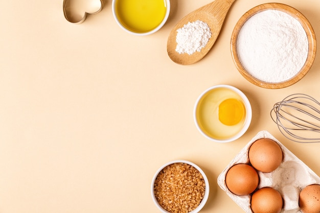 Ingredients and utensils for baking on a pastel background, top view.