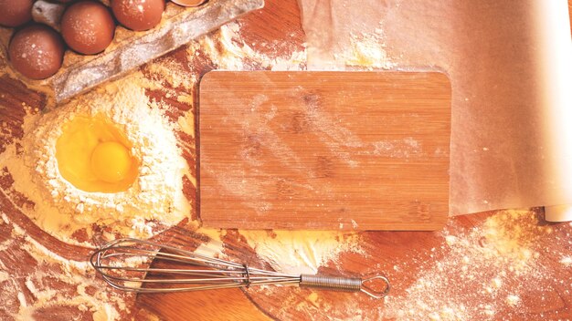 Photo ingredients and utensils for baking on a pastel wooden background, top view. concept of kitchen, cooking and easter