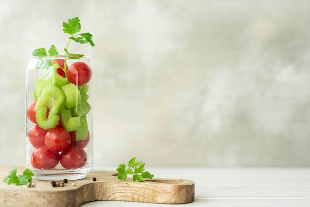 Ingredients for vegetable smoothie tomatoes and celery in a glass jar