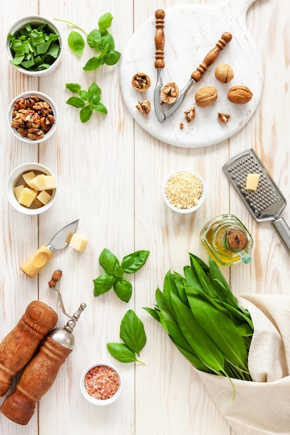 Ingredients for Wild Garlic Pesto cooking delicious savory sauce for Italian pasta Ramson herbs cheese walnuts basil olive oil Top view on white background