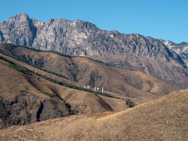 Ingushetia Mountain view Ancient towers complex in Ingushetia Russia Impressive rocky wall of the Caucasus mountains is on the background