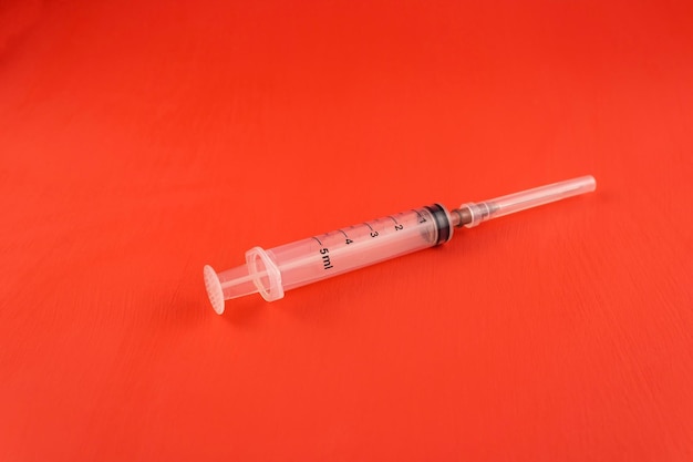 Injection syringe closeup on a red background