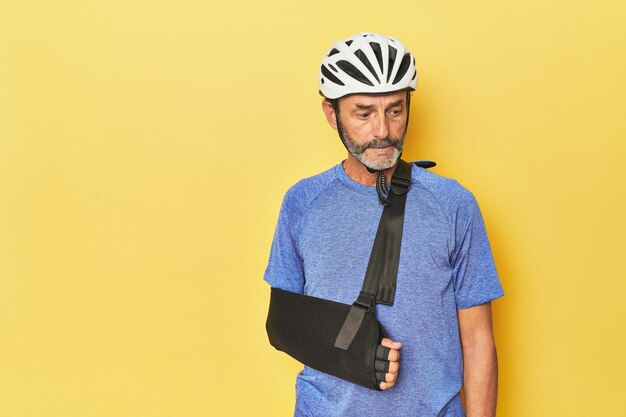 Injured cyclist wearing sling looks sorrowful