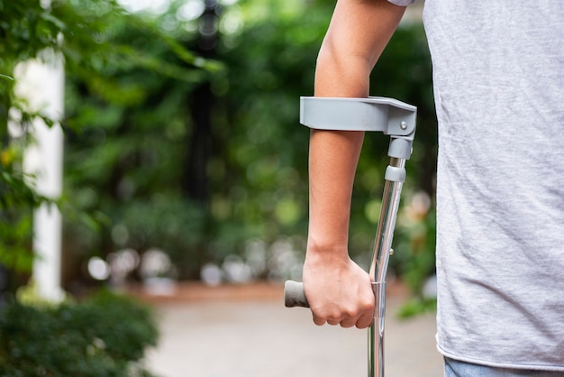 An injured man tries to walk on crutches the park on a blurred background