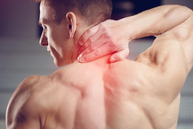 Injured neck Young handsome muscular athlete having neck pain Sport fitness and health care concept