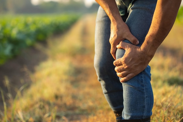 Injuries or Illnesses that can happen to farmers while working Man is using his hand to cover over knee because of hurt pain or feeling ill