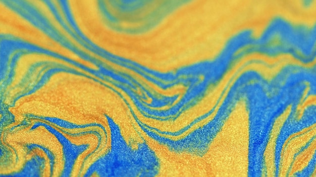 Ink glitter liquid sparkles yellow colored particles motion down blue painted sand strips abstract