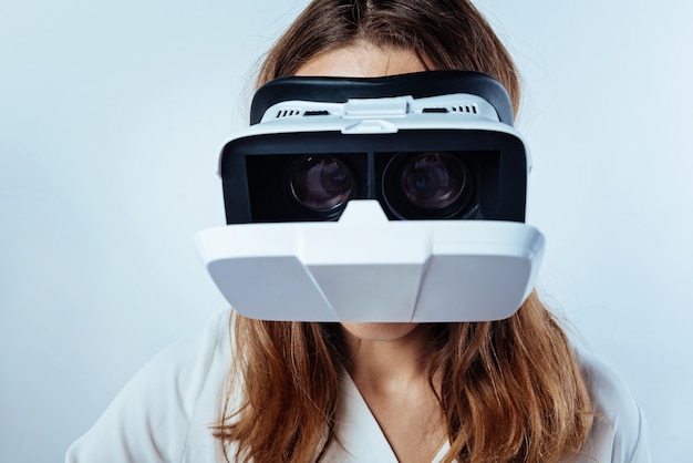 Innovative technologies. Scaled up look on young lady trying on visual reality glasses and playing games over the background.