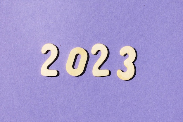 Inscription 2023 with wooden numbers on purple background Festive concept