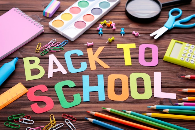 Inscription Back To School with school supplies on brown wooden  surface