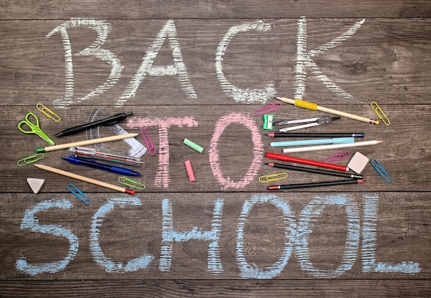  Inscription back to school with school tools on a wooden background