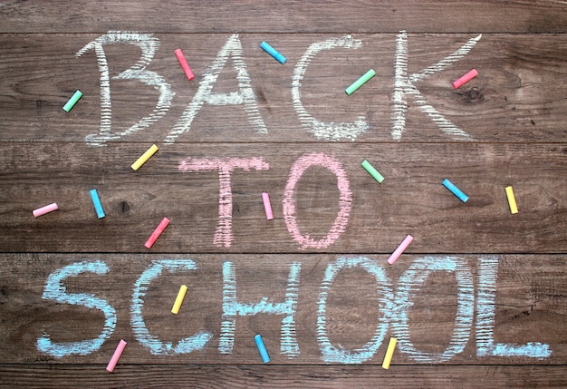  Inscription back to school on a wooden background and colored chalk