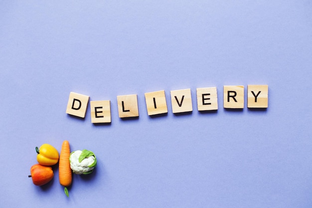 Inscription delivery with vegetables and fruits on purple background delivery service concept