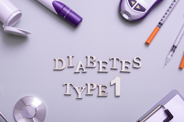 Inscription diabetes type 1 and glucometer syringes and medical equipment on a colored background top view