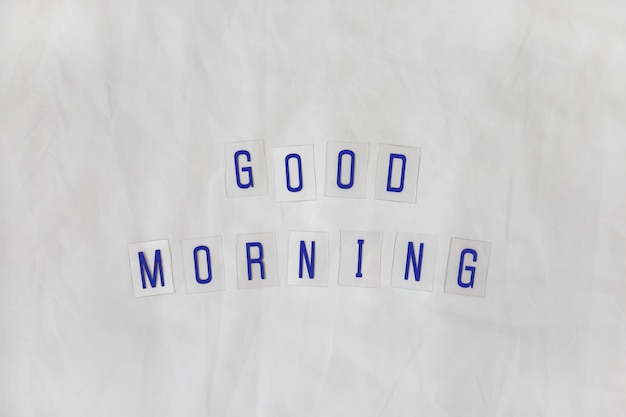 Inscription Good morning, composed of dark blue letters on transparent plastic bases on white