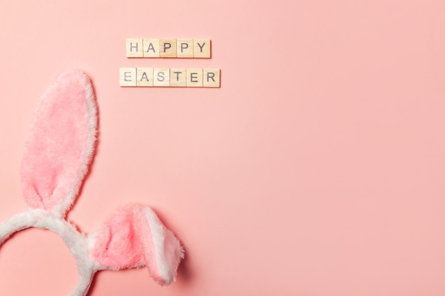 Inscription HAPPY EASTER, bunny ears isolated on pink background