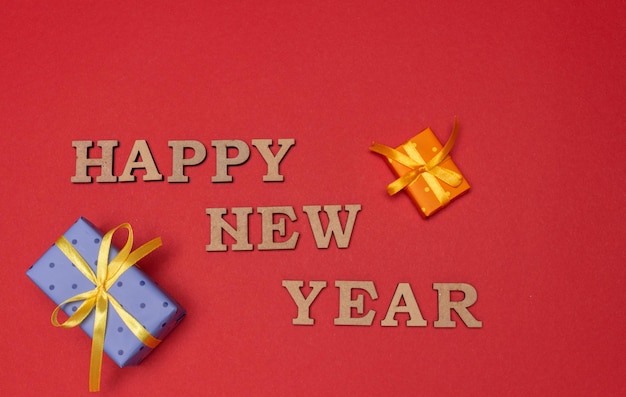 Inscription Happy New Year and gift boxes with ribbons on red background. Christmas and New Year