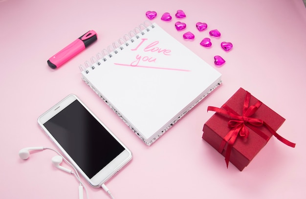 Photo the inscription i love you in a notebook next to a gift and a smartphone valentines day