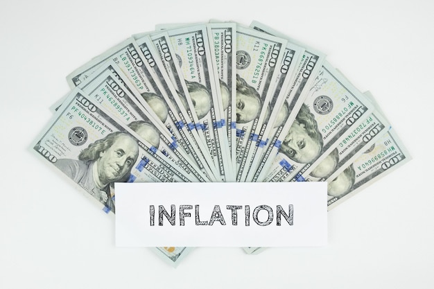 Inscription inflation on the background of scattered dollar bills on a white background