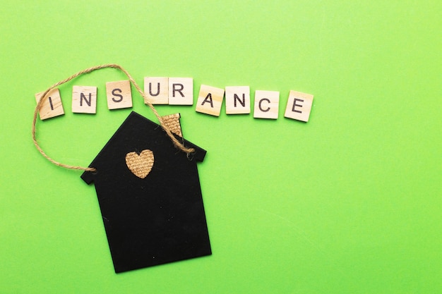 Inscription insurance with a little house on a green background made by wooden blocks