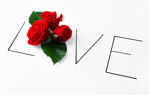 Inscription love with red roses on white background