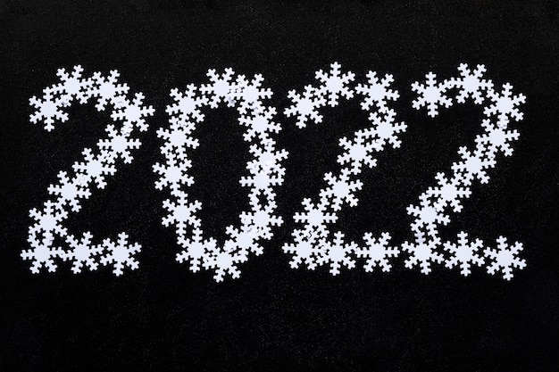 Inscription made of beautiful white snowflakes on a dark black chalkboard background new year and