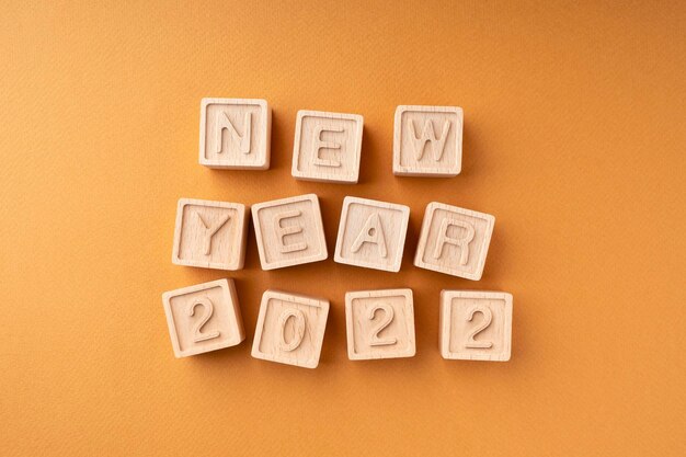 The inscription new year 2022 on wooden cubes Wooden cubes with letters on an orange background New Year's card