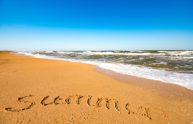 The inscription on the sand summer near the stormy sea wave on a sunny warm summer day. Concept of the long-awaited summer holiday and vacation