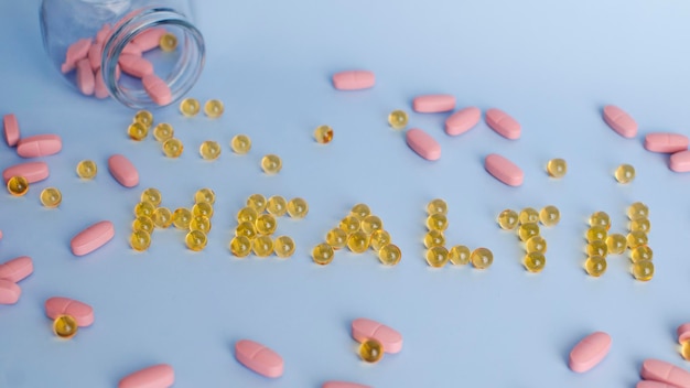 The inscription text health laid out from tablets and vitamins on a blue background yellow pink