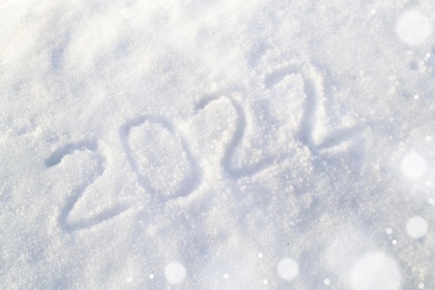 inscription on white snow surface with defocused lights text draw on snow happy new year concept