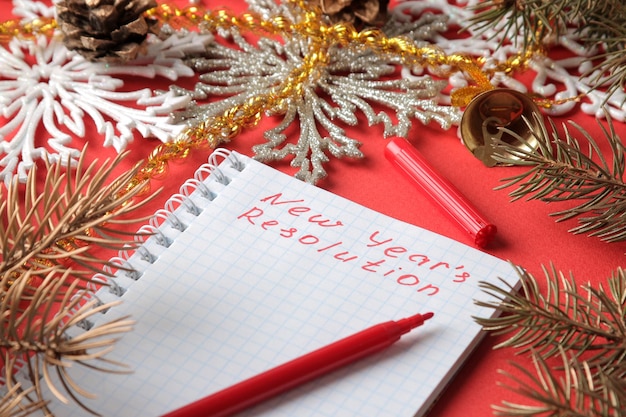 Inscriptions New Year's resolution in a notebook and various New Year's decorations on a red background. New Year Christmas. holidays