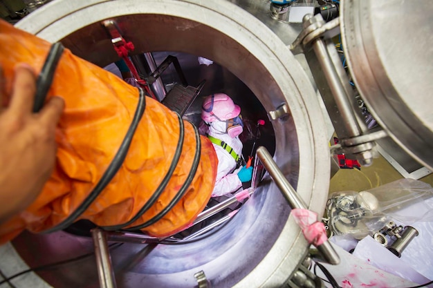 Inside male two worker into the inspection shiny tank stainless chemical blower fresh air into area confined space