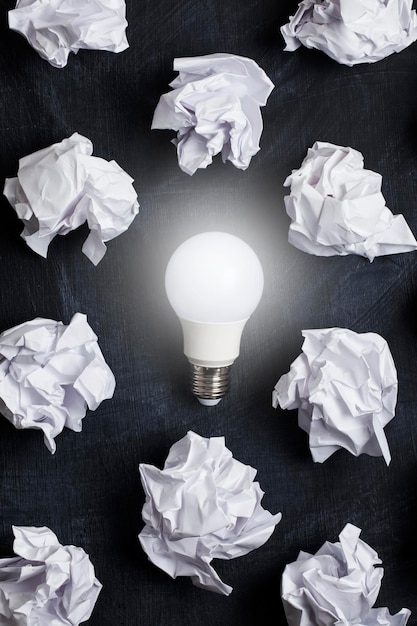 Inspiration and imagination concept lightbulb with white crumpled paper documents