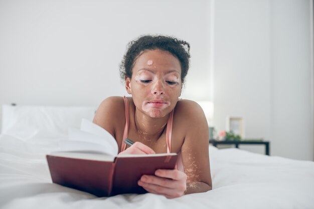 Inspiration. A young woman writing in her diary and looking inspaired