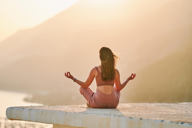 Inspired happy female sitting on top and enjoying of meditation with beautiful view at sunset time Relief stress and healthy minds