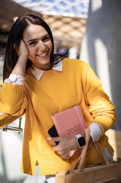 Inspired young business woman with a smile and holding coral colored diary