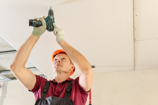 Installation of drywall using and a screwdriver to attach plasterboard to the ceiling