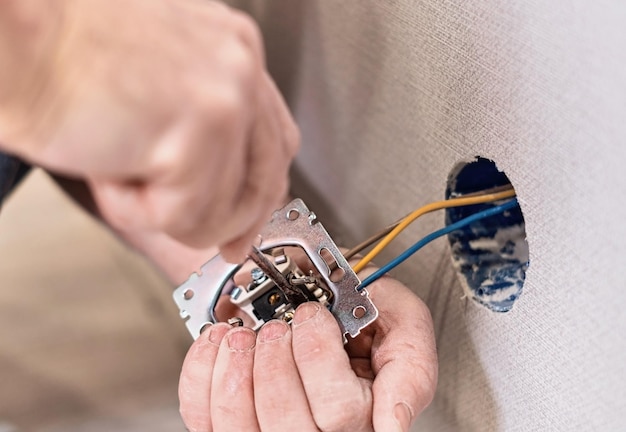 Installation of electrical sockets Hands an electrician installing an electrical network in a new house Selective focus on the electrical sockets