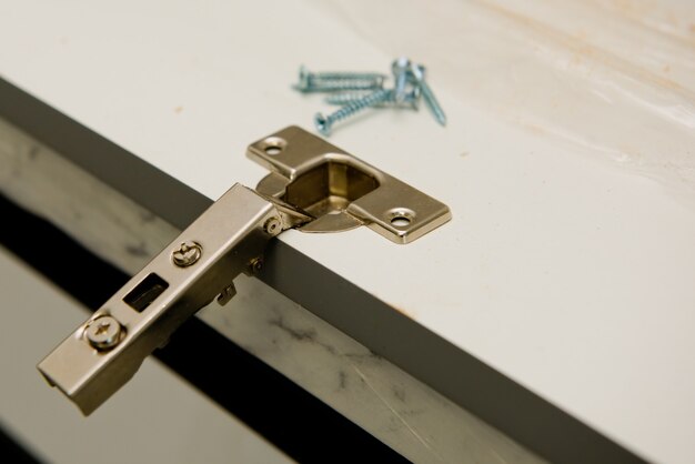 Photo installation of metal hinges to the chipboard. selective focus. close up.