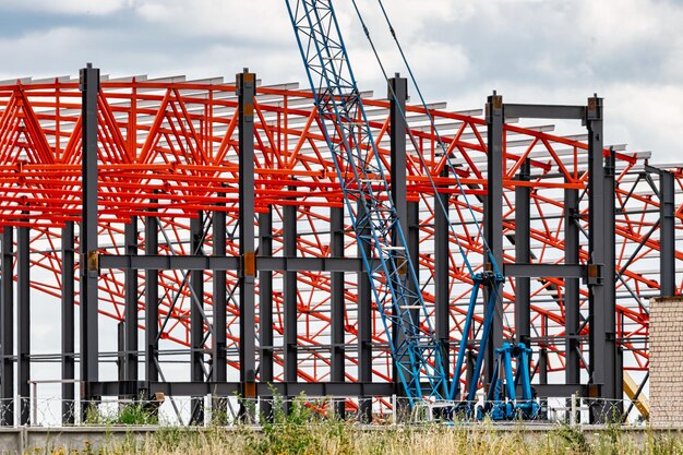 Installation of metal trusses and frame during the construction of an industrial building or factory The work of installers during the installation of the roof Construction of a large frame shop