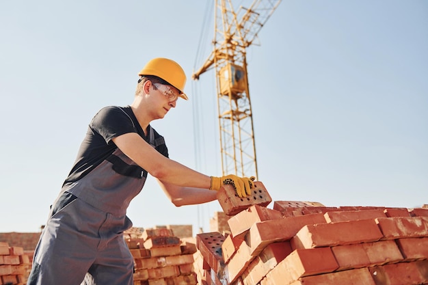 Installing brick wall Construction worker in uniform and safety equipment have job on building