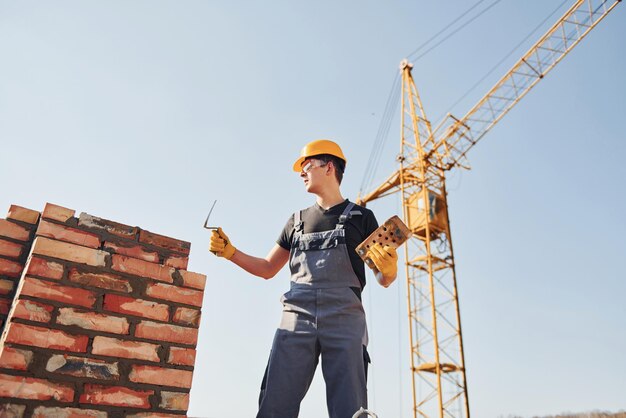 Installing brick wall Construction worker in uniform and safety equipment have job on building