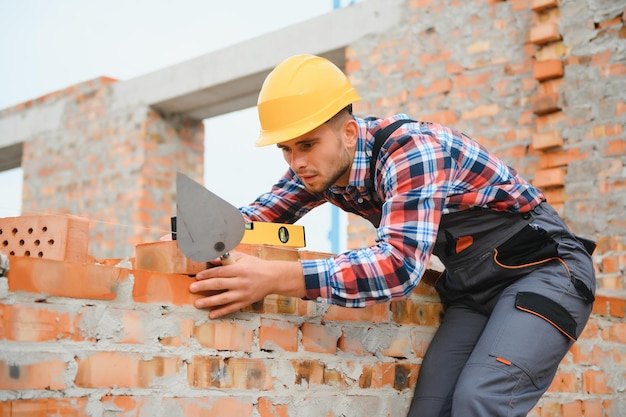 Installing brick wall Construction worker in uniform and safety equipment have job on building