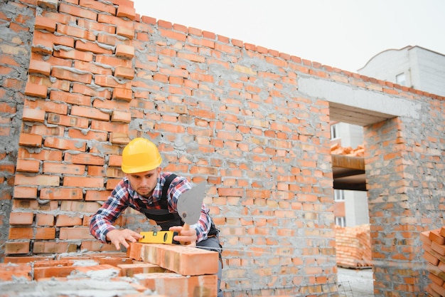 Installing brick wall Construction worker in uniform and safety equipment have job on building