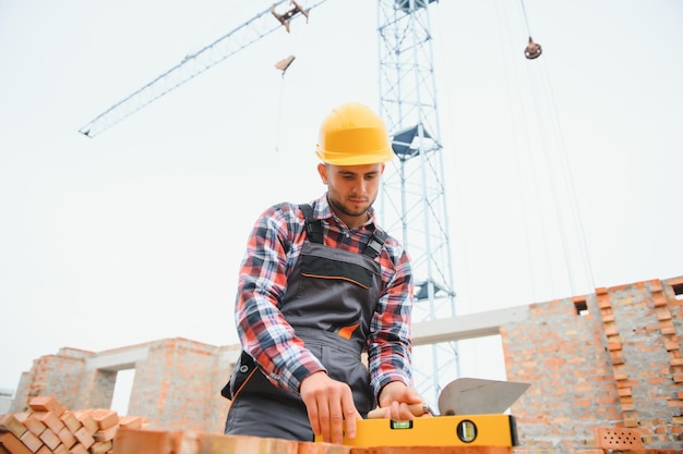 Installing brick wall Construction worker in uniform and safety equipment have job on building