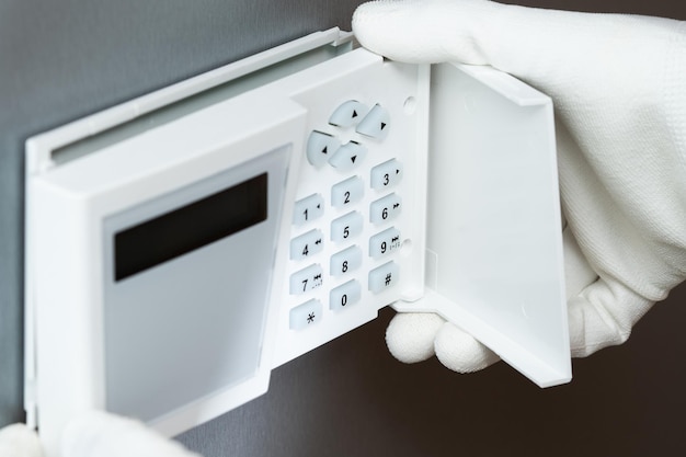 Installing a security systems keyboard on a gray wall