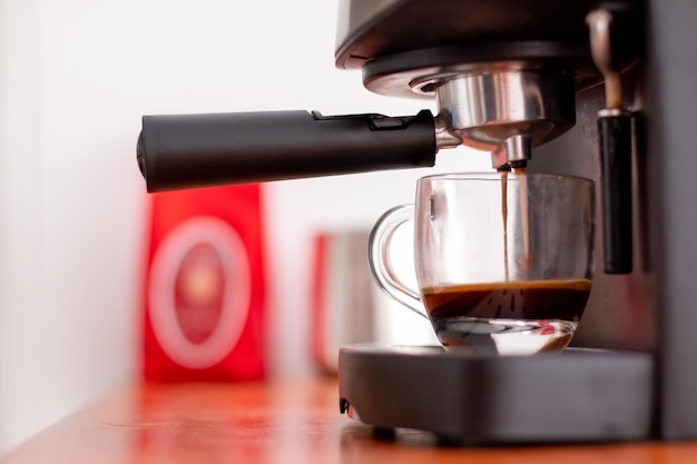 Instant coffee machine preparing coffee in a half-filled transparent cup.