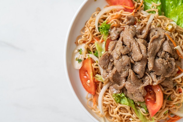 instant noodle spicy salad with pork on white plate - Asian food style