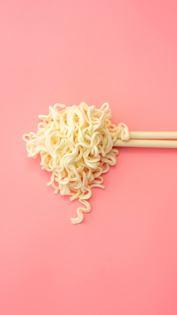 Instant noodles and chopsticks on pink 